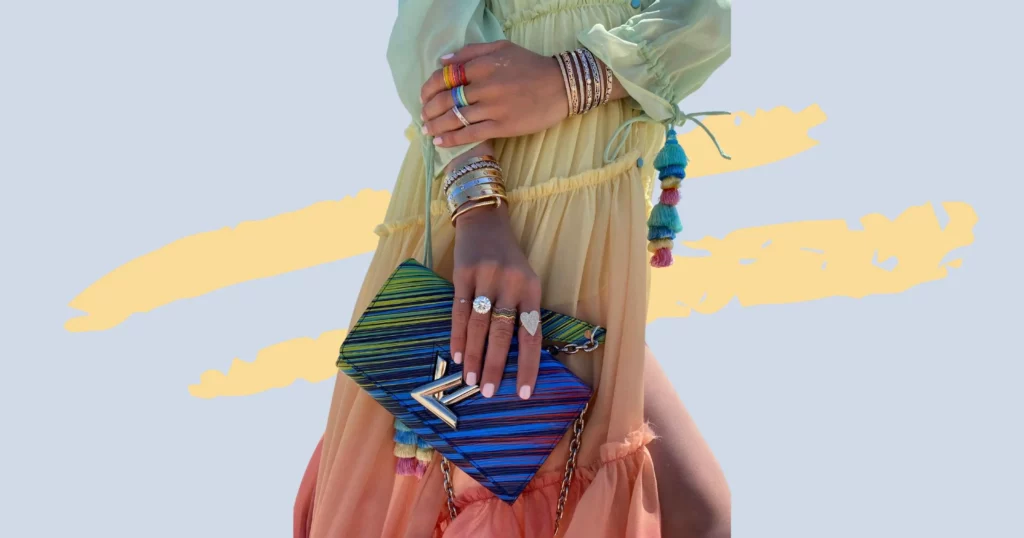 close up of a woman's hands and arms wearing bracelets and rings and holding a designer purse from vivrelle