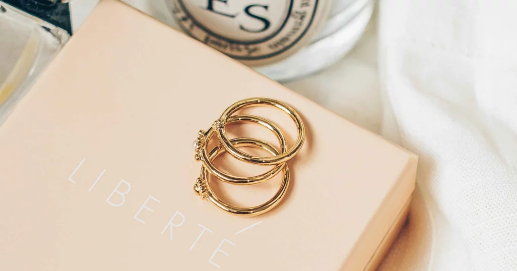 3 gold rings overlapping each other on a pink jewelry box that says Liberte