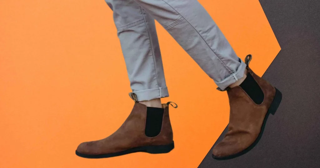 closeup of someone wearing brown Blundstone Chelsea boots and gray pants