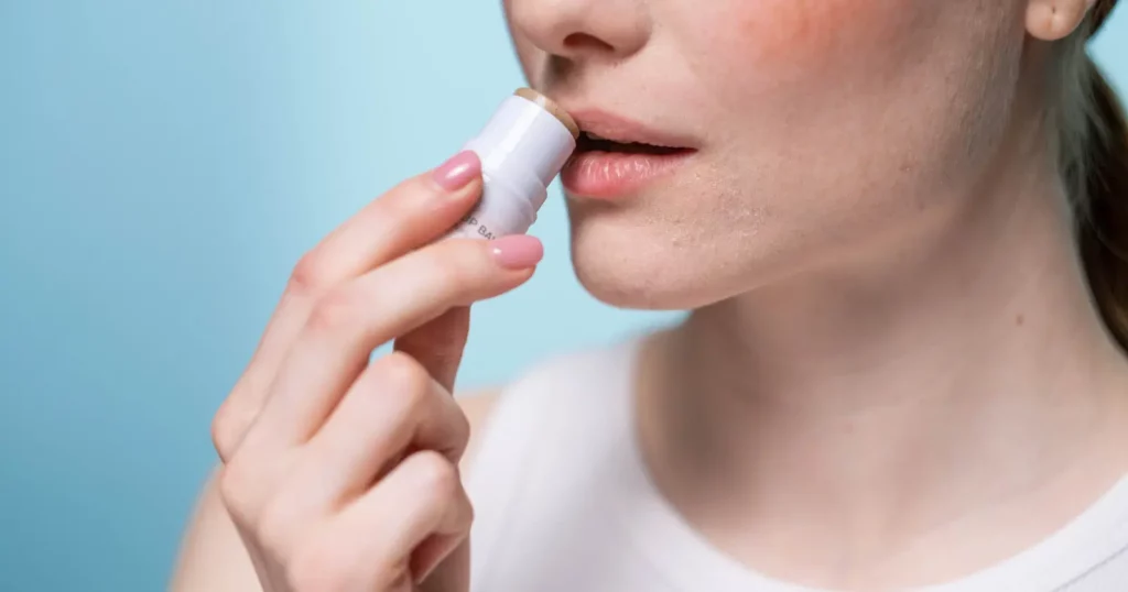 close up of woman applying lip balm to lips