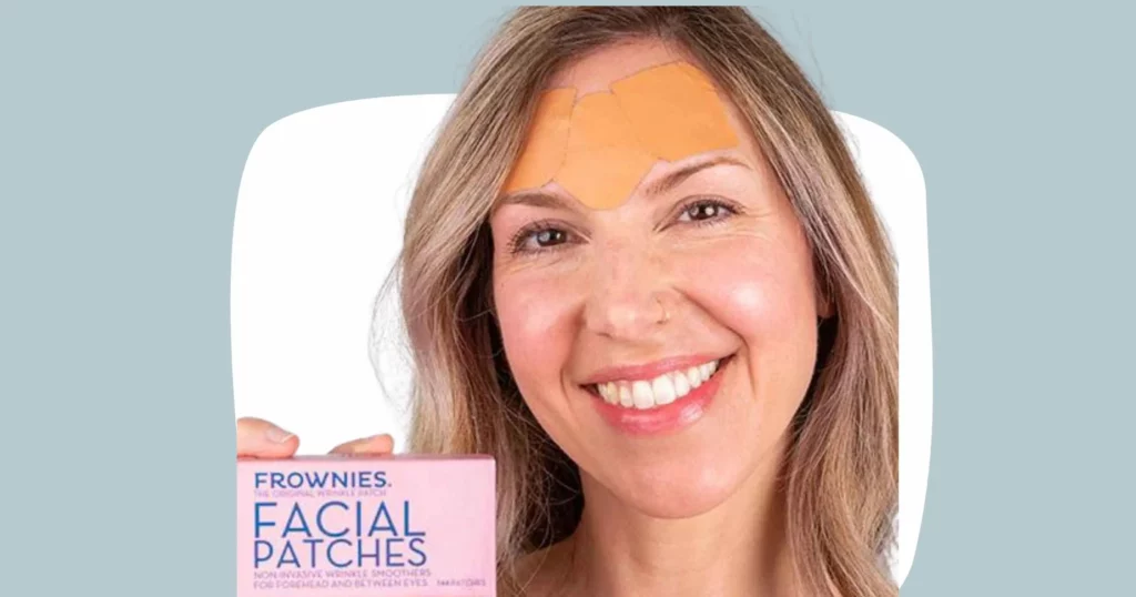 head shot of woman smiling, wearing Frownies facial patches on forehead, and holding a box of Frownies facial patches