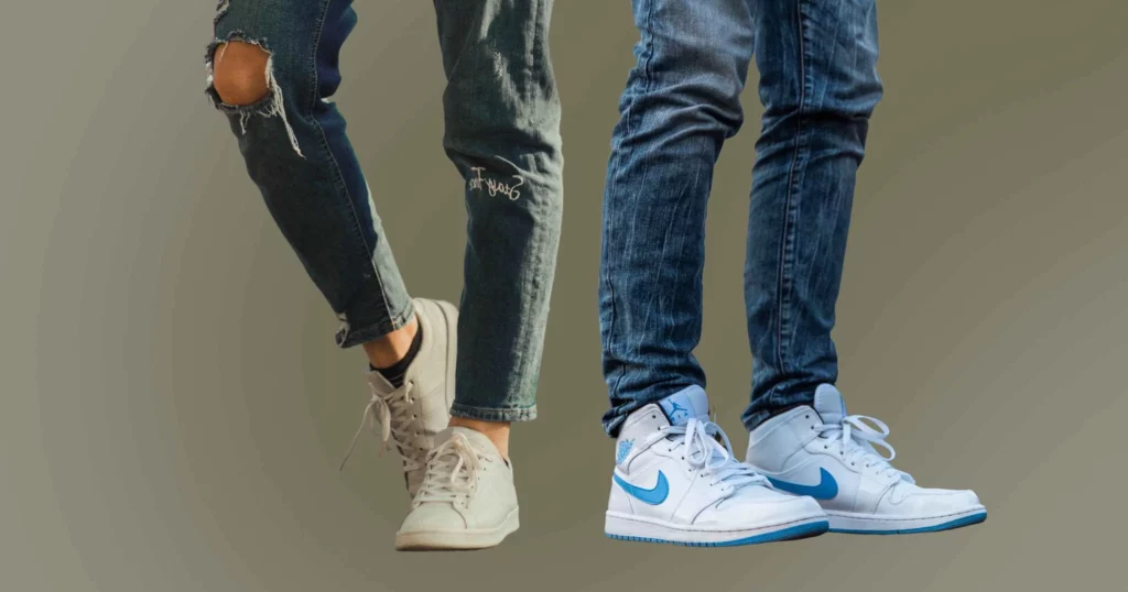 close-up of two sets of legs and feet, one person wearing athletic fit jeans and white shoes, another person wearing slim fit jeans and white shoes
