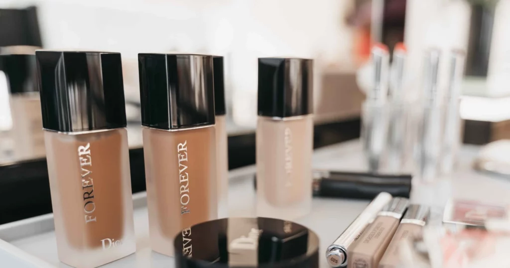 bb cream vs foundation: row of liquid foundation bottles and other makeup products on table