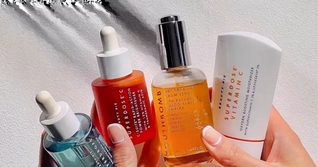 close up of person's hands holding different colored bottles of Beauty Pie products
