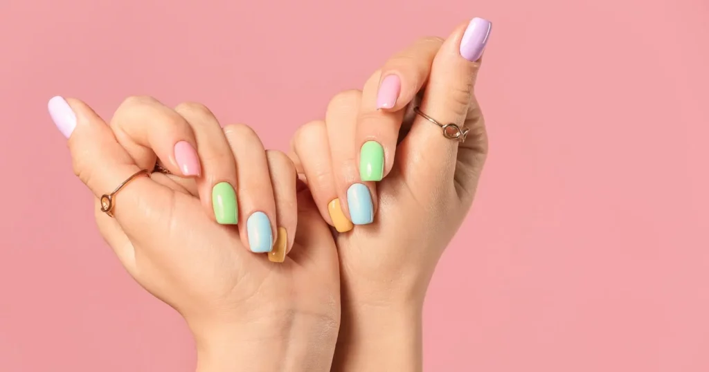 close up of person's hands with different pastel colored nails
