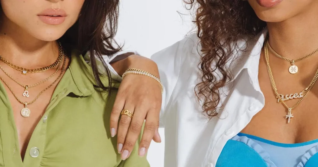 closeup of two women wearing jewelry from The GLD Shop including necklaces, bracelets, and rings