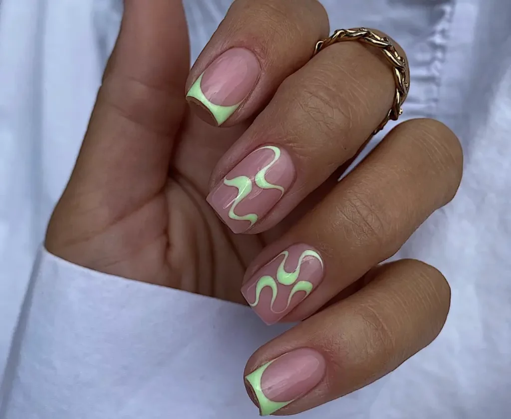 trendy nail design with neon green abstract squiggle lines on the two middle nails, and neon green tips on the rest of the nails, with a clear nail underneath