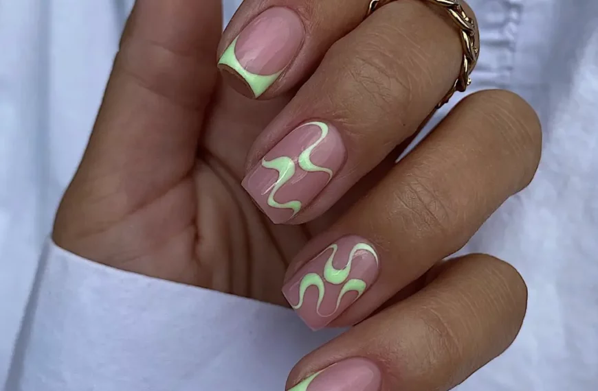 trendy nail design with neon green abstract squiggle lines on the two middle nails, and neon green tips on the rest of the nails, with a clear nail underneath