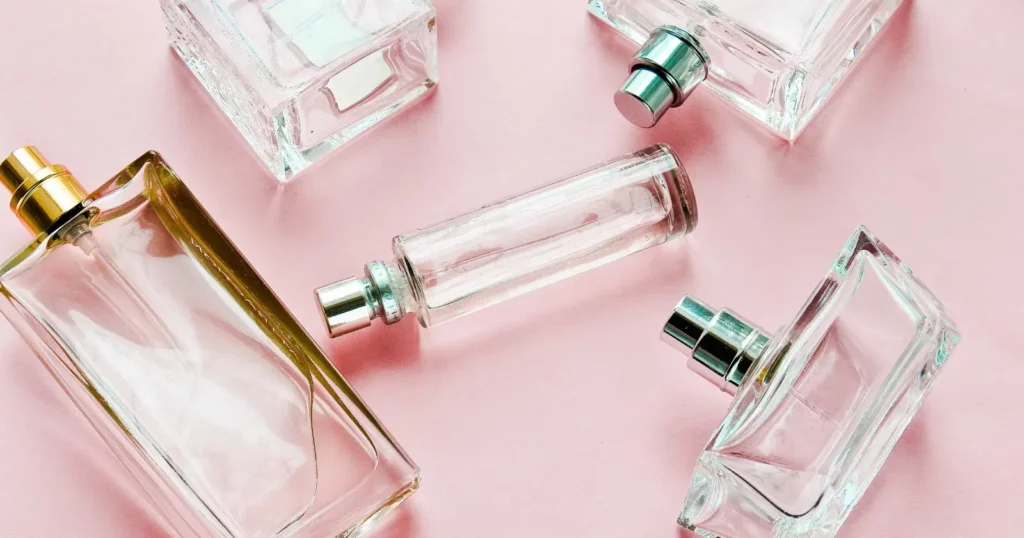 scattered clear perfume bottles against pink background