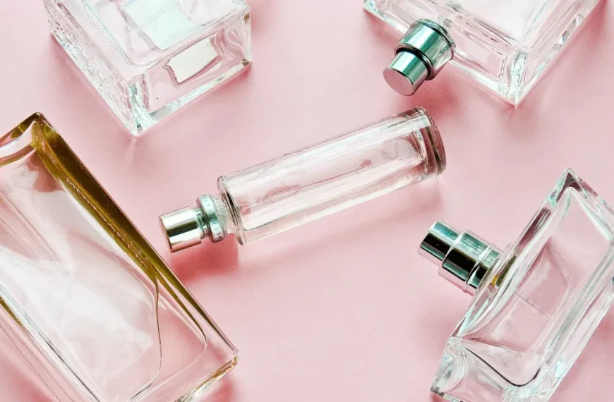 scattered clear perfume bottles against pink background