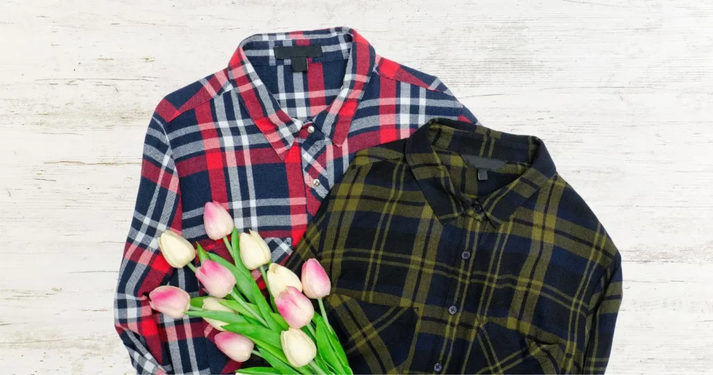two flannel shirts with plaid patterns: one red, blue, and white, the other yellow and black. There are flowers on top of the shirts