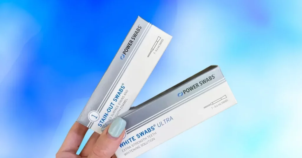 person's hand holding up two Power Swabs whitening solution boxes
