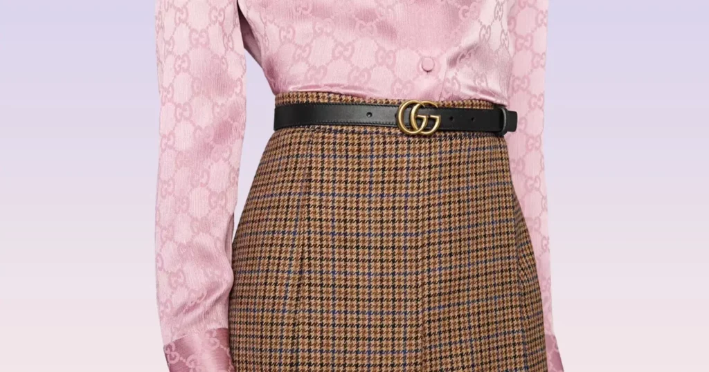 closeup of person wearing pink top, patterned skirt, and Gucci black leather double g belt