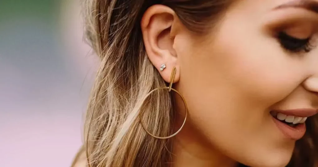 side profile of woman's face, wearing gold hoop earring and crystal stud earring from Maison Miru