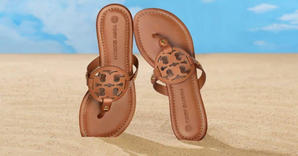 brown Tory Burch Miller Sandals standing up on sand with blue sky in background