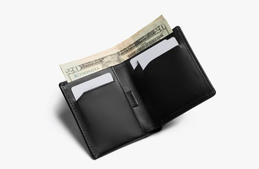 slim bellroy wallet in black open and filled with cards and money sticking out the top